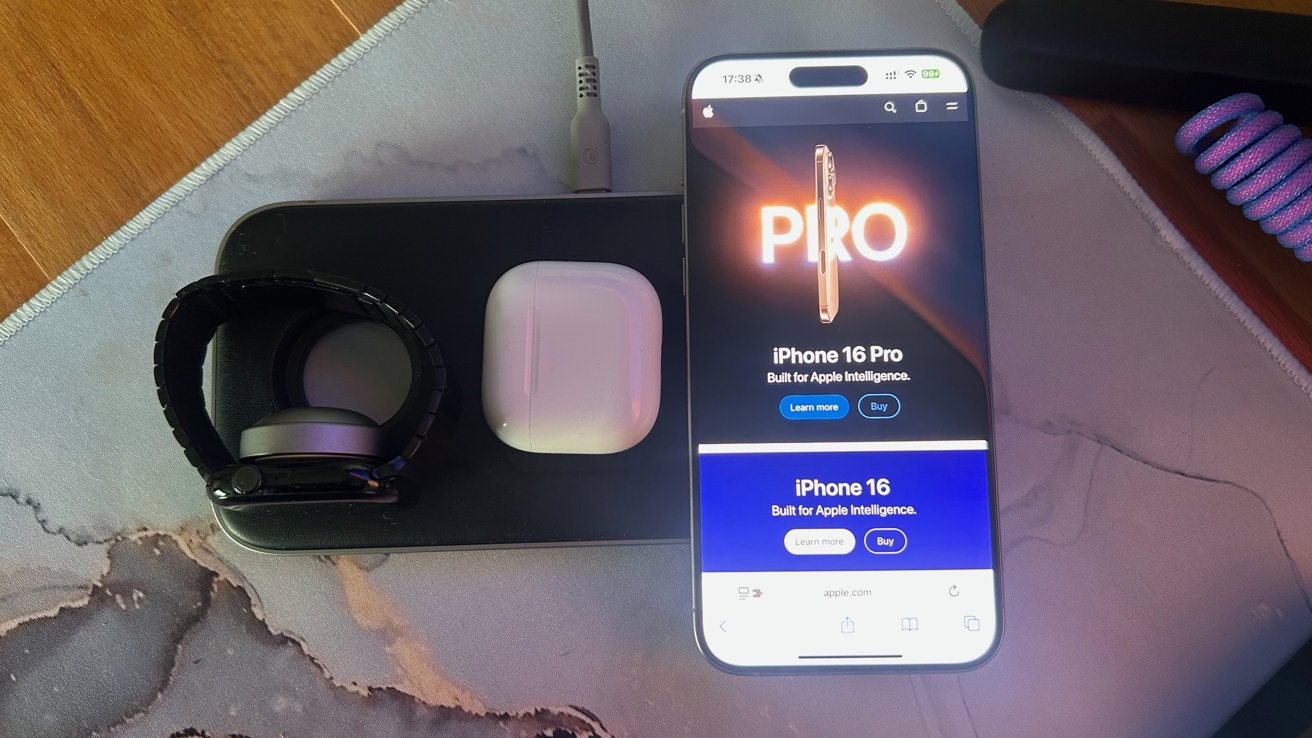 Smartwatch, wireless earbuds, and a smartphone displaying an advertisement for the iPhone 16 Pro on a charger.